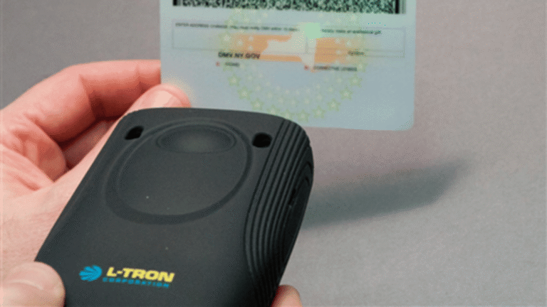 An advanced handheld scanner processing a digital credential displayed on a mobile phone screen inside a public safety vehicle.